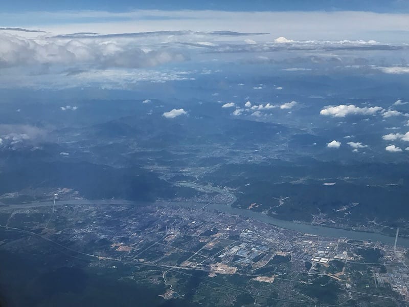 The Fuchun River bending through low green hills, seen from above, with the county town in the foreground